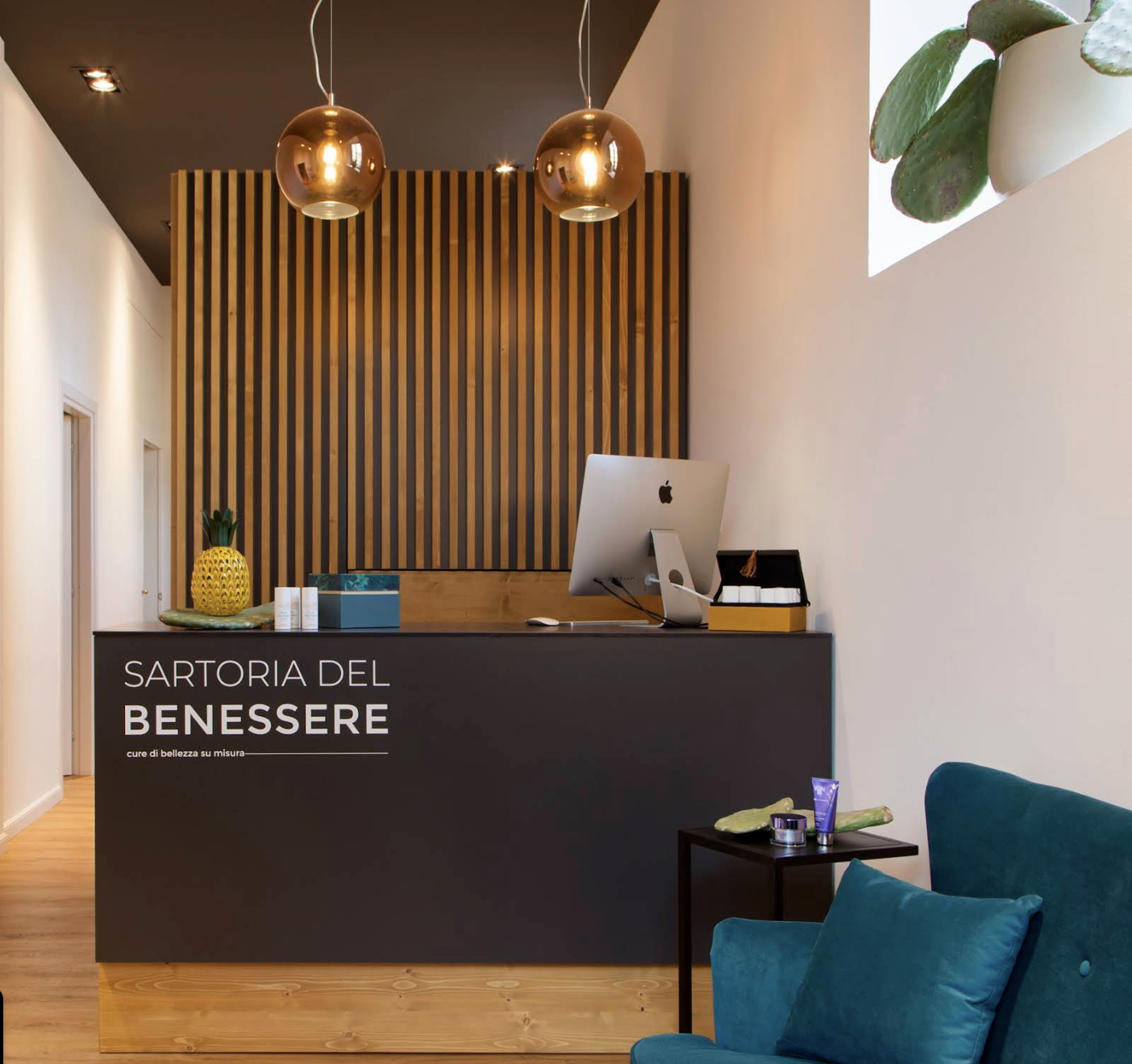 Reception Sartoria del Benessere — bancone nero, lampade rame